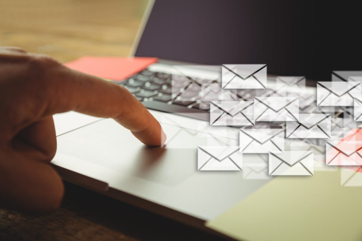 composite image of hand using laptop put on a desk with letter icons